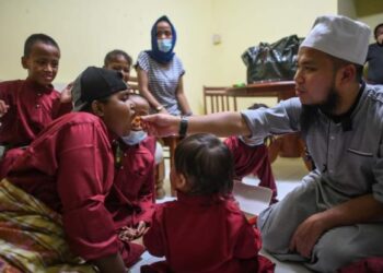 EBIT Lew (kanan) menyuap makanan kepada salah seorang kanak-kanak yang dibantunya selepas menyediakan kediaman kepada keluarga terbabit di Johor Bahru, Johor.