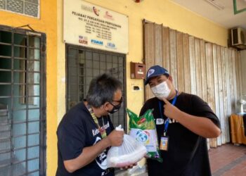 Ahmad Hashim (kanan) menyerahkan bantuan kepada seorang penerima.