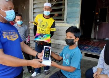 ABD. HALIM Shafai menyerahkan telefon pintar kepada Muhammad Haris Adam Izrail di rumahnya di Jalan Pasar Lama, Wakaf Bharu, Tumpat, Kelantan.