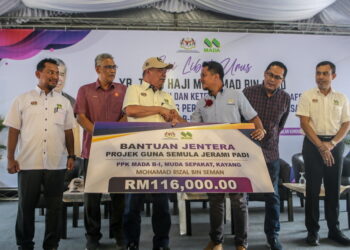 MOHAMAD Sabu menyampaikan sumbangan Bantuan Jentera Projek Guna Semula Jerami Padi kepada salah penerima, Mohamad Rizal Seman ketika Sesi Libat Urus Bersama Pimpinan Peladang MADA di PPK B-IV, Pengkalan Kundur, Alor Setar. -UTUSAN/ SHAHIR NOORDIN