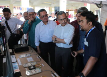 FAHMI Fadzil (tengah) mendengar taklimat daripada wakil TM mengenai hab gentian optik ketika hadir ke Majlis Perasmian Hab Gentian Optik Pop Zon Utara di SMK Padang Terap di Kuala Nerang. -UTUSAN/ SHAHIR NOORDIN