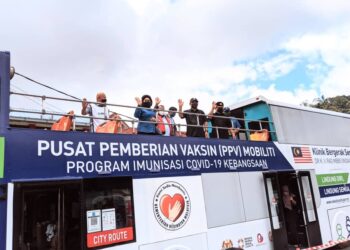 RONALD Kiandee (depan, tengah) di atas bas persiaran yang diubah suai menjadi tempat pemberikan vaksin Covid-19 di bawah program AiVAC di Dewan Serbaguna Kampung Raja, Cameron Highlands hari ini. - UTUSAN/MOHAMAD HAFIZI MOHD. SAID