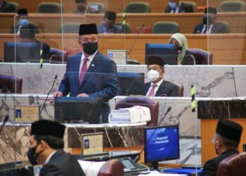 HASNI Mohammad (kanan) bersama Muhyiddin Yassin (tengah) mengangkat tangan pada sesi pengundian sebulat suara Belanjawan Johor 2022 di Bangunan Kota Iskandar, Iskandar Puteri.