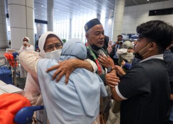 MOHD. Amri Abdul Rahman (tengah) disambut oleh ahli keluarganya ketika kumpulan pertama jemaah haji selamat tiba di KLIA, Sepang, Selangor. - UTUSAN/FAISOL MUSTAFA