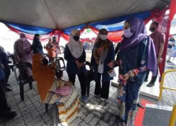 HALIMAH Mohamad Sadique (kanan) berbual dengan seorang peniaga yang hadir menerima vaksin melalui program MOVAK untuk penjaja dan peniaga kecil Daerah Kota Tinggi di Dome Dataran Tun Sri Lanang, Kota Tinggi, Johor. - FOTO/MASTURAH SURADI