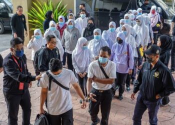 PEGAWAI Jabatan Pendaftaran Negara (JPN) mengiringi 29 tertuduh warga Indonesia yang didakwa atas pertuduhan memiliki kad pengenalan palsu di Mahkamah Majistret Petaling Jaya, hari ini. - FOTO/FARIZ RUSADIO