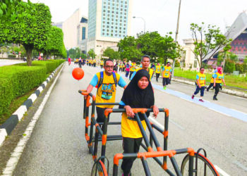 Wan Muadzam (belakang) membantu pelajar OKU menggunakan alat bantu berlari, CABALLUS RAFVI.