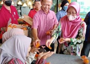 DR. ZALIHA MUSTAFFA (kanan) mengagihkan buah limau menjelang sambutan Tahun Baharu Cina diserikan dengan tarian singa di U Central, Bandar Utama, Segamat.