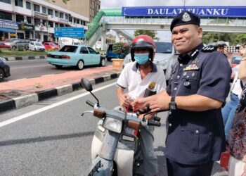 BAHRAIN MOHD. NOH menyerahkan beg yang mengandungi risalah keselamatan jalan raya kepada pengguna dalam Op Selamat 19 di Kilometer 51, Jalan Batu Pahat-Mersing.