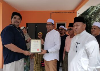 NAJIB SAMURI (dua dari kanan) menyerahkan sijil pemilikan rumah kepada Md. Hizam  di Kampung Parit Yaani Tengah, Batu Pahat.