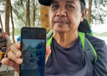 ISHAK KAMIS menunjukkan gambar Muhamad Akmal yang disyaki hilang di Pulau Mawar selepas mendaki di kawasan tersebut pada Rabu lalu.