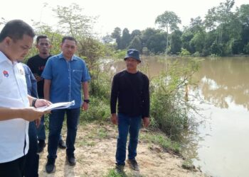 ZAHARI SARIP melihat kertas cadangan projek pembinaan jeti terapung di tebing sungai di Kampung Seberang Batu Badak, Segamat.