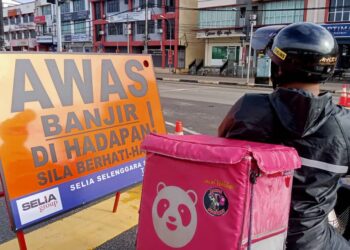 ZAHID NOOSHAM tetap menjalankan tugasnya menghantar pesanan pelanggan sebelum terkandas di Bandar Segamat yang digenangi banjir.