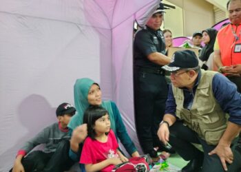 SAIFUDDIN NASUTION ISMAIL (kanan) menyerahkan bantuan kepada mangsa banjir yang ditempatkan di PPS di Dewan Orang Ramai Kampung Melayu, Kluang.