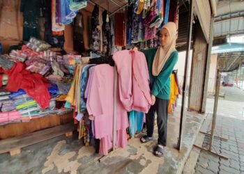 NOOR SHAFINA NAIM menunjukkan pakaian yang terjejas akibat banjir yang melanda kedai pakaian milik bapanya di Kota Tinggi.