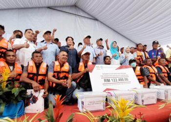MOHAMAD SABU (tengah) bergambar dengan penerima Bantuan Nelayan Pengerang di Kompleks LKIM Pengerang, Kota Tinggi.