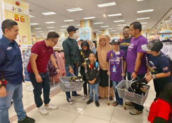 MUHAMMAD DURRANI FARIS NOR ARIFIN (bertongkat) ditemani bapanya menerima bantuan persekolahan pada Program Kembali Ke Sekolah anjuran Empire Project di AEON Mall, Kulai.