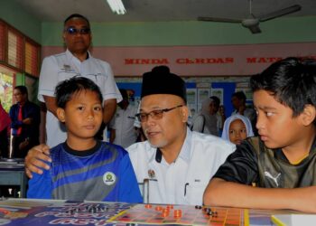 MD. SAID MD. DAIMON beramah mesra dengan Muhammad Akmal Lutfi Mohd. Harol (kanan) dan Muhammad Daniel Iqbal Firdaus yang merupakan mangsa banjir pada hari pertama sesi persekolahan 2023/2024 di SK Sri Pandan, Batu Pahat.