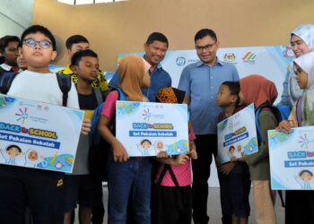AKMAL NASRULLAH MOHD. NASIR (tengah) beramah mesra dengan murid-murid yang menerima kelengkapan sekolah sambil diperhatikan oleh Mohd. Norlisam dan Rafidah pada Majlis SWM Kasih Back To School di Dewan Flat Larkin, Johor Bahru.