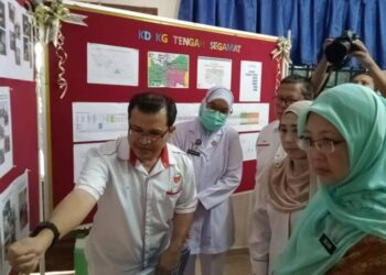 DR. ZALIHA MUSTAFA (kanan) mendengar penerangan daripada Dr. Zaid Kassim tentang kejadian banjir yang melanda Klinik Desa  Kampung Tengah, Segamat semasa meninjau klinik berkenaan.