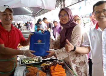 ZALIHA MUSTAFA (dua dari kanan) menyampaikan apron kepada seorang peniaga Bazar Ramadan di Bandar Utama, Segamat.