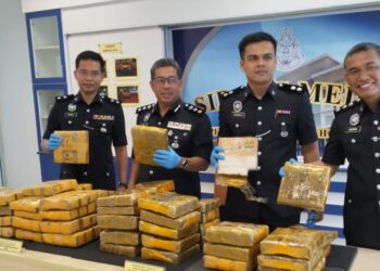 ISMAIL DOLLAH (dua dari kiri) menunjukkan ketulan mampat ganja yang dirampas daripada seorang lelaki di Yong Peng, Batu Pahat.