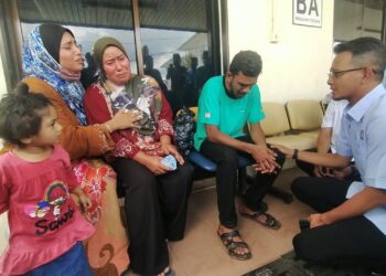 NABILA SEDU (duduk tengah) ditenangkan oleh salah seorang ahli keluarganya ketika ditemui Mohd. Fared di pekarangan Jabatan Forensik HPSF, Muar.