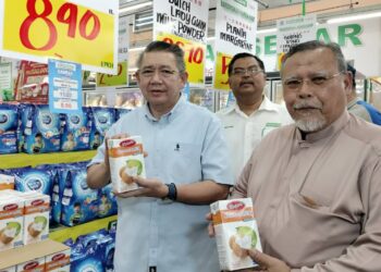 SALAHUDDIN AYUB (kiri) menunjukkan sebahagian daripada barangan keperluan yang diberikan potongan harga di Pasaraya Econsave Yong Peng, Batu Pahat.