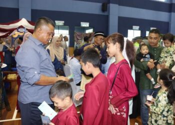 KAMARUL ZAMAN MAMAT memberi duit raya kepada kanak-kanak pada Majlis Rumah Terbuka Aidilfitri anjuran Ibu pejabat Polis Daerah Iskandar Puteri, semalam.