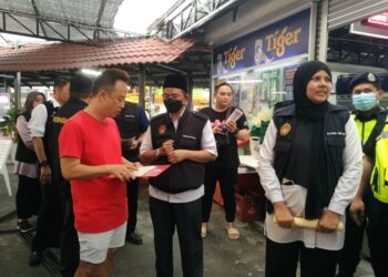 DR. MOHTAR PUNGUT (tengah) memberi penerangan kepada seorang pengusaha kedai makan tentang kesalahan yang boleh dikenakan tindakan di bawah PPKHT 2004 dalam Operasi Mega Bersepadu di Taman Abad, Johor Bahru.
