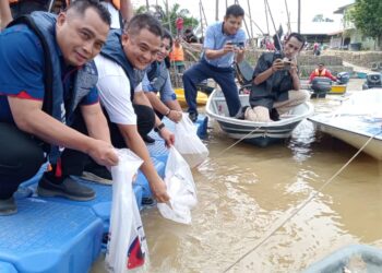 ZAHARI SARIP (dua dari kiri) melepaskan benih ikan serta udang ke perairan negeri Johor di Jeti Kampung Tekam, Segamat.