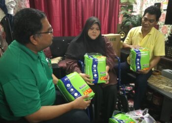 MAS IMRAN ADAM (kiri) menyampaikan sumbangan kepada Fadzil dan isterinya ketika melawat mereka di PPR Setia Indah, Johor Bahru.