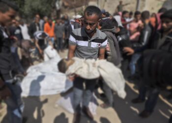 PEMUDA Palestin mengangkat mayat kanak-kanak lelaki yang terbunuh sebelum dikebumikan di Beit Lahya, utara Gaza. -AFP