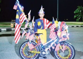 MUHAMMAD Amirul Rashid bersemangat memakai pakaian bertemakan Jalur Gemilang dan basikal yang dihiasi bendera tersebut bagi menyemarakkan lagi sambutan bulan kebangsaan 2021 ketika ditemui Utusan Malaysia di Pantai Saujana, Port Dickson, semalam.-UTUSAN/ZAKKINA WATI AHMAD TARMIZI.