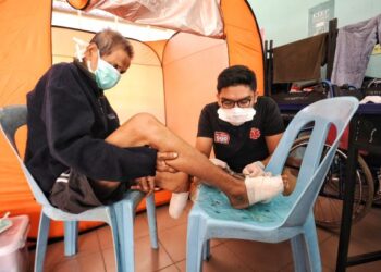 MANGSA banjir, Abdul Malek, 65, menerima rawatan daripada seorang petugas kesihatan ketika berada di PPS SK Jimah Lama, Port Dickson, hari ini.-UTUSAN/MOHD SHAHJEHAN MAAMIN.