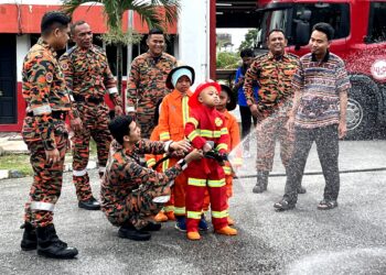 ANGGOTA bomba menunjukkan cara-cara memadamkan kebakaran kepada Ahmad Akif pada program yang diadakan di Balai Bomba Senawang, Seremban hari ini.-UTUSAN/ZAKKINA WATI AHMAD TARMIZI.