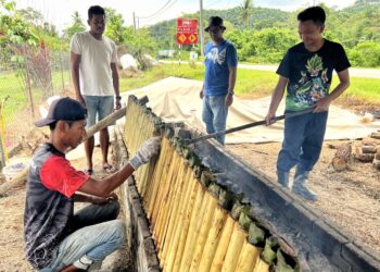 ZAINAL Abdullah (kanan) bersama tiga orang sahabatnya memasak lemang di gerai mereka yang terletak di Kampung Pantai, Seremban.-UTUSAN/ZAKKINA WATI AHMAD TARMIZI.