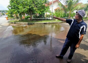 MOHD. Jamaludin Mohd. Rashid menunjukkan air longkang yang melimpah keluar ke atas jalan sehingga membawa masalah bau busuk dan jalan licin kepada penduduk di Taman Harmonium dan Taman Bukit Kepayang di Seremban.-UTUSAN/MOHD. SHAHJEHAN MAAMIN.