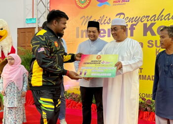 MUHAMMAD Sanusi Md. Nor menyampaikan replika cek berjumlah RM10,000 kepada atlet sukan memanah, G. Daneshen yang meraih tiga emas pada Majlis Penyerahan Insentif Kemenangan Para Sukma XX di Kompleks Belia dan Sukan di Alor Setar. -UTUSAN/JAMLIAH ABDULLAH