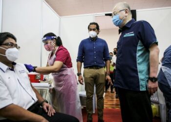 WEE Ka Siong dan  Khairy Jamaluddin (kanan) melihat petugas kesihatan memberi suntikan vaksin Covid-19 kepada pekerja laut dan pekerja pelabuhan ketika lawatan ke Pusat Pemberian Vaksin (PPV) Sektor Pengangkutan (Maritim) di Dewan Kompleks Sukan Pelabuhan Klang. -  UTUSAN/ZULFADHLI ZAKI