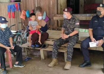 MOHD. YUSRI Hassan Basri (duduk, dua dari kanan) dan disaksikan Mustapa Long (kiri) beramah mesra dengan seorang penduduk selepas menyampaikan bantuan di Kampung Mentara Baru di Lipis, Pahang. - UTUSAN/HARIS FADILAH AHMAD