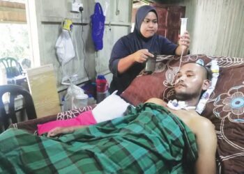 NUR KHAIRUL BARIAH MOKHTAR memberi susu khas kepada suaminya, Muhammad Faizal Hakimi Mat Jusoh yang terlantar di Kampung Tengkawang, Hulu Terengganu. - UTUSAN/NOOR HAYATI MAMAT