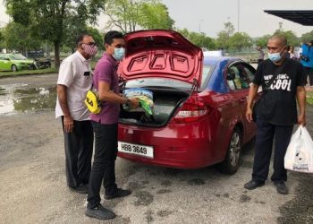 SUKARELAWAN Al-I'tisam (tengah, berbaju ungu) memasukkan barang bantuan ke dalam sebuah teksi di hentian teksi Seksyen 13, Shah Alam hari ini. - FOTO/MOHAMAD NAUFAL MOHAMAD IDRIS