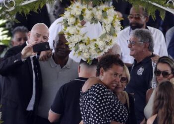 Gianni Infantino (kiri) menerima kritikan selepas berswafoto di sebelah keranda Pele ketika memberi penghormatan kepada legenda bola sepak Brazil itu di Stadium Urbano Caldeira, Santos, Brazil semalam.