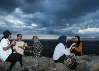 BEBERAPA pelanggan menikmati suasana matahari terbenam sambil menikmati kopi di County’s Kopi di pantai Kampung Kurung Tengar, Kuala Perlis, semalam. –  UTUSAN/IZLIZAN OTHMAN