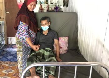 SITI Zaiton menemani suaminya yang hilang upaya untuk berjalan akibat serangan strok di rumah mereka di Kampung Bendang Pak Yong, Tumpat. – UTUSAN/ROSLIZA MOHAMED