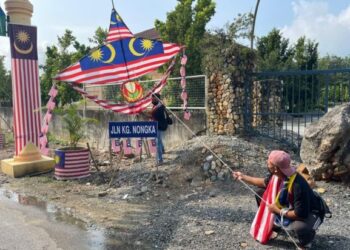 Muhammad Shahrul Hashim (kanan) dan Mohd. Taqyuddin Ali menyiapkan kerja-kerja membina replika wau bulan yang dihiasi Jalur Gemilang di Kampung Nongka, Napoh di Changlun, Kubang Pasu semalam. 
– UTUSAN/ABD. RAZAK OSMAN