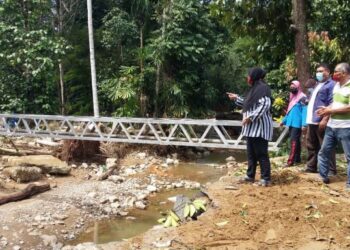 PENDUDUK Kampung Setol melihat sisa-sisa bekas runtuhan jambatan Kampung Setol dibersihkan bagi memulakan pembinaan jambatan sementara di Yan, Kedah, semalam. - UTUSAN/OTHMAN YAHAYA