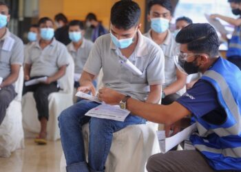 SEORANG petugas membantu pekerja industri mendaftar bagi penerimaan vaksin Covid-19 di PPV Pikas d’Tempat Country Club, Sendayan, Seremban,Negeri Sembilan,  baru-baru ini.-UTUSAN/MOHD. SHAHJEHAN MAAMIN
