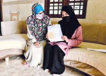 MAIZATUL Aisyah Umairah Mohammad (kanan) bersama ibunya menunjukkan kad rawatan doktor di rumahnya di Kampung Beris Panchor, Bachok Kelantan.- UTUSAN/ROSLIZA MOHAMED